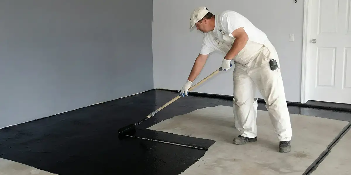 basement waterproofing professional applying waterproof coating to protect a basement floor in Atlanta, GA